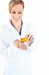 Charming young doctor holding pills against a white background
