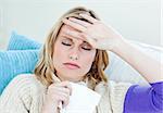 Sick woman with headache lying on the sofa in the living-room at home