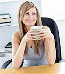 Relaxed businesswoman holding a cup of coffee in her office at her desk