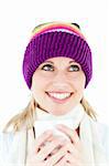 Merry young woman holding a cup wearing a cap in the winter against white background