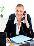 Radiant businesswoman talking on phone in her office at her desk