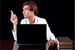 young businessman on the computer on a black background. Studio shot