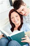 Charming young couple reading a book lying on the sofa in the living-room