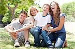 front view of happy family sitting in park and posing for camera