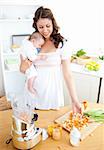 Caring young mother preparing vegetables for her baby in the kitchen at home