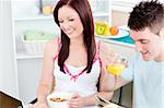 Bright couple using a laptop while breakfast at home