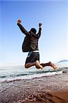 A happy business man jumping by the ocean - happy successful concept