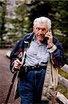 A senior talking on a cell phone outdoors in the forest