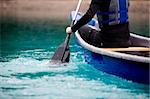 A person paddling a canoe in a turquoise galcier water