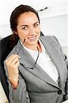 Joyful hispanic businesswoman holding glasses and smiling at the camera in her office