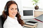 Delighted hispanic businesswoman with headset sitting at her desk in a call center