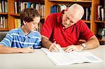 Father helps his son with homework, in the library.