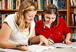 Two pretty teen girls doing their homework in the school library.