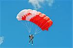 The parachutist under a pink parachute against the blue sky