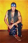 Kneeling Native American man with tattoos and vest