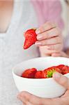Close-up of a pregnant woman eating a bowl of strawberries at home