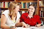 Two teenage girls studying together in the school library.