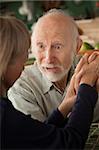 Senior couple at home in kitchen holding hands focusing on man