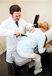 Chiropractor using an eletrical tool and computer to diagnose and adjust a patient's spine alignment.