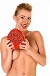 Friendly sexy blond with breasts covered by arms opening heart shaped gift box
