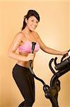 Young woman sweaty while working out on elliptical machine