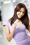 Portrait of the beautiful happy girl in the shop, holding in a hand a credit card