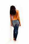 Back view of young woman with bare top wearing worn jeans