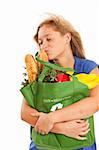 Humorous portrait of young woman with green recycled grocery bag kissing food