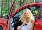 beautiful woman driver in red shiny car opens the door