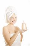 Young beautiful woman with healthy pure skin and white towel on her head holding moisturising cream in bathroom
