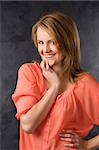 fashion beauty portrait of young woman with hair style over dark background wearing an orange shirt and smiling