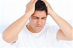 Man suffering from a migraine on waking sitting in his bedroom