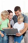 Adorable family working together on a laptop sitting on the sofa in the living-room