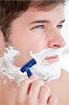 Bright caucasian man shaving in the bathroom at home