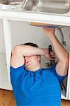 Tired man repairing his sink in the kitchen at home