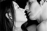 Young adult Caucasian couple in passionate embrace and kissing each other during sexual foreplay. High contrast black and white