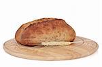 Wholegrain bread loaf on a rustic wooden bread board with wheat ear sprig, isolated over white background.