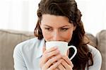 Pretty businesswoman drinking coffee on the sofa at home