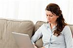 Serious businesswoman working on her laptop on the sofa at home