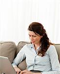 Beautiful businesswoman working on her laptop on the sofa at home
