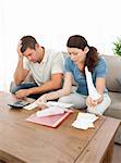Worried couple looking at their bills in the living room at home