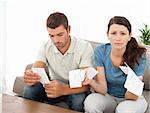 Desperate woman doing her accounts with her boyfriend sitting on the sofa at home