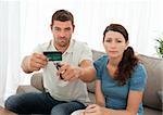 Worried couple cutting their credit card together sitting on the sofa at home