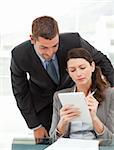 Handsome businessman speaking to a female colleague while working at her desk in the office