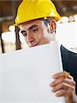 caucasian male architect examining blueprint. Vertical shape, waist up, side view, copy space