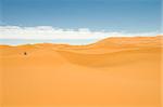 Woman sitting alone into the sand dunes of the Sahara desert. Best of Morocco.