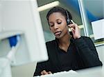 female african american customer service representative with headset typing on computer. Horizontal shape, front view, waist up