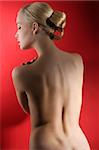 naked blond woman showing her back in a fashion elegant shot with hair stylish over red