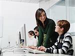 Computer lab with caucasian female teacher helping student. Horizontal shape, side view, waist up, copy space