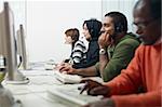 Multiethnic computer class with indian, middle eastern, hispanic and caucasian people training with pc. Horizontal shape, side view, waist up